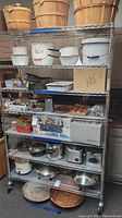 Front view of the 7-tier rolling NSF metal shelf unit showing baskets, cookware, and other items on the shelves.