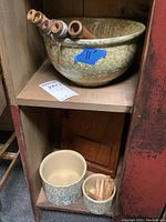 Top shelf showing large 11-inch spongeware bowl with mottled glaze and wooden spools inside, and below two smaller Robinson spongeware crocks with wooden spools inside and a flat wooden board behind