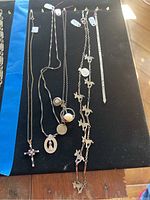 Full view of five necklaces and one anklet on black display cloth.