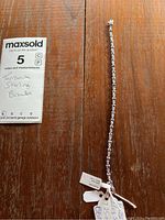 Full length of the bracelet laid flat showing linked tanzanite stones and bracelet tag details.