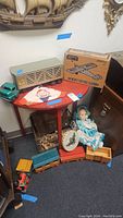 Wide shot of toys and red demilune table displaying the items