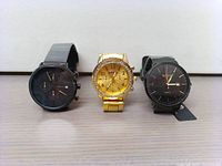 Three analog watches side by side: a gold Geneva watch centered, flanked by two black watches, one Carjuu with subdials on left and one Biden on right