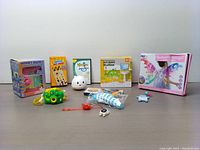 Full group of toys and accessories included in the lot arranged on a table, including the money box, bath bubble machine, butterfly wings, and smaller toys.