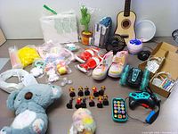 Wide view of the entire children's bundle lot showing all included toys, shoes, guitar, and accessories.