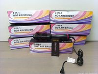 Eight boxed 3-in-1 hot air brushes stacked together with one unboxed brush in front showing package and brush design.