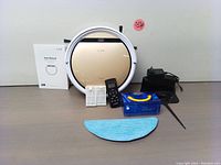 Front view of ILIFE V5s Plus vacuum with accessories including remote, user manual, charger, replacement filter, mop cloth, and cleaning tool arranged on a flat surface.