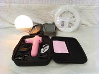 Close-up photo of the massage gun and attachments in the carrying case along with instruction manual.