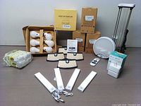 Full view of the lot showing various boxed LED lights, smart plugs, solar sensor lights, remote control, and UV sanitizer displayed on table.