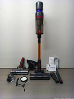 Full front view of the SmartVac vacuum cleaner standing upright with all attachments and accessories laid out in front including brush heads, charger, filter, and manuals.