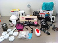 Overview of all bundle items on table including hair straightener brush box and assorted home appliances