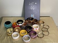 Photo of assorted women's bangles with various colors and designs arranged on a beige surface.