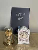 Front view showing both clocks: ceramic clock with floral patterns on the right and gold-toned clock under dome on the left.