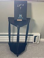 Front view of the dark brown wooden corner table with a small shelf beneath the top surface. Shows the shape and leg design clearly.