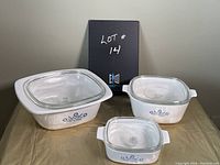 Front view of three Cornflower Blue CorningWare casserole dishes with lids arranged on a surface.