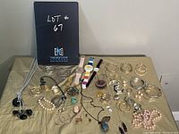 Full display of costume jewelry lot on a gold fabric background including earrings, bracelets, necklaces, and watches