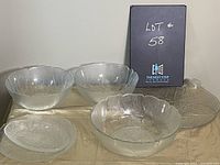 Five vintage glass bowls and plates arranged on a surface showing clear leaf pattern and scalloped edges.