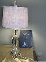 Front view of the glass table lamp with faceted glass stem and light purple textured drum shade.