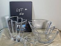 Photo showing the clear crystal vase with vertical angular facets, bowl with stepped edges, and the small rounded dish arranged on a surface with a neutral backdrop and black box behind labeled Lot 50.