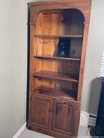 Full front view of the pine cabinet showing four open shelves and the two-door enclosed bottom cabinet with wood grain and knots visible.