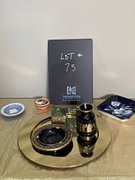 Full collection shown on gold tray: Wedgewood plate, black and gold vase, black and gold dish, green trinket box, hexagonal floral dish, small round trinket container, small cylindrical container