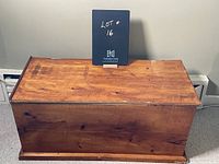 Front angle view of the wooden storage chest showing the broken top lid and wood grain.