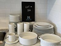 Overview showing stacks of plates, mugs, cups on saucers and two bowls on countertop