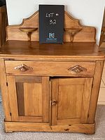Front view of the vintage pine cabinet showing drawer, cupboard doors, and shaped upper back panel with shelves.