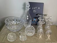 Full lot of glass and crystal items including decanter, glasses, bowl, and smaller pieces arranged on a table.
