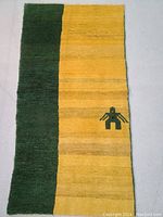 Full view of rectangular Gabbeh rug with dark green and yellow color blocks and small motif.