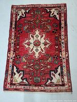 Full view of red and cream Persian rug with detailed floral and geometric design on floor