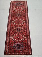 Full length view of runner rug laid flat on floor showing overall multi medallion pattern and borders