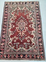 Full view of the Persian Mahal rug showing decorative flower pattern and floral borders in shades of red, cream, green, and black.