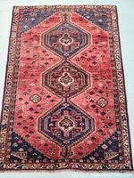 Full view of the hand-knotted red and navy tribal medallion rug laid flat