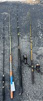 Four fishing poles laid out on asphalt, showing overall length and condition.