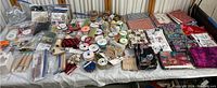 Wide shot of multiple crafting supplies on a table including ribbons, wood products, fabric, and other craft accessories