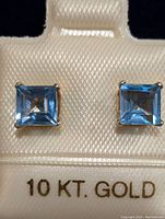 Top-down view of both square-cut blue topaz stud earrings in 10K gold setting.