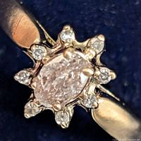 Close-up front view showing oval pink diamond center and surrounding white diamond halo