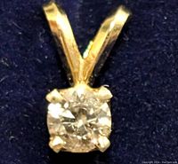 Close-up image of 14K gold diamond pendant front view on dark background.