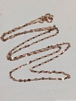 Full view of the 18K rose gold chain necklace laid out showing its length and detail of links.