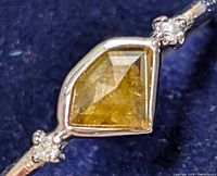 Close-up image of yellowish kite-shaped diamond set in 10K gold ring with small clear accent diamonds on band.