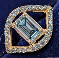 Close-up of ring top showing emerald-cut center and halo diamonds