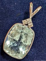 Clear top-down photo of pendant showing aquamarine and diamond cluster on blue background