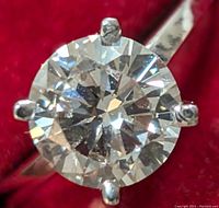 Close-up of round brilliant-cut diamond face and six-prong setting on red velvet background