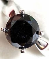 Top-down view of round black diamond in six-prong setting