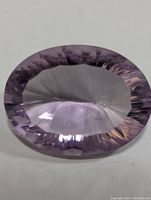 Top view of oval cut amethyst displaying light purple color and faceting details.