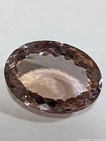 Close-up front view of oval faceted pale purple amethyst gemstone showing clarity and checkerboard facets.