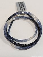 Photo showing multi-strand bracelet coiled with faceted blue sapphire beads and tag indicating bracelet details