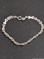 Full view of bracelet laid out on black fabric showing the linked design and clasp