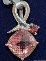 Close-up photo of the silver pendant showing the faceted pink quartz and the red gemstone set above with the loop bail