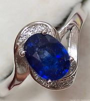 Close-up front angle of sterling silver ring with oval sapphire center and pavé stones